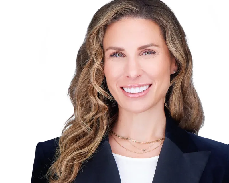 Bright LinkedIn headshot of a smiling woman on a white backdrop